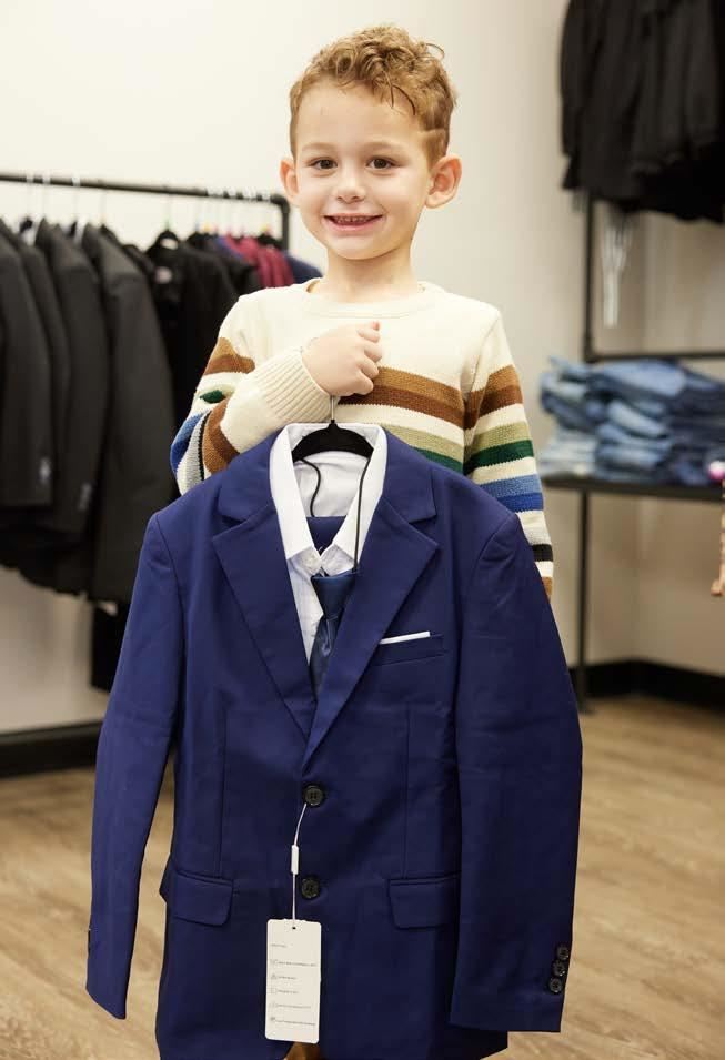 Gunner Hartman enjoys shopping at AIDB THREADS. He smiles at the camera while wearing a striped sweater.